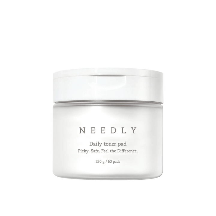 En vit burk med Needly Daily Toner Pad. Förpackningen har minimalistisk text som beskriver produkten och innehåller 280 g, motsvarande 60 tonerpads. Texten lyder 'Picky. Safe. Feel the Difference.